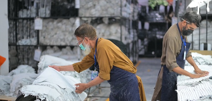 Two manufacturing technicians inspecting and sorting fabric bundles at workstation tables in the Maswiz Industries factory facility.